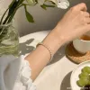 A golden oval-shaped bracelet set with light-colored gemstones, a fashionable and elegant women's jewelry accessory, is presented as a gift details Picture